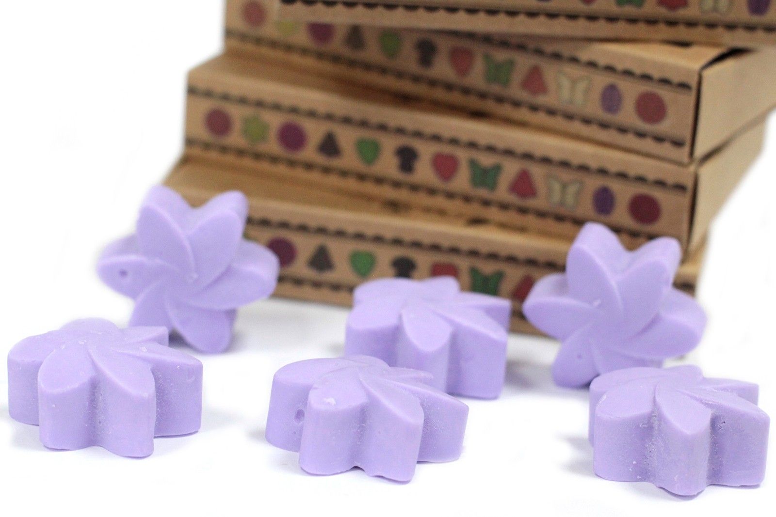 Purple butterfly-shaped wax melts on a white surface with a decorative box in the background.